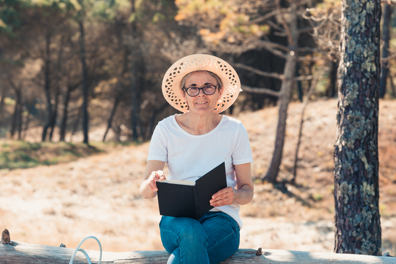 old woman reading a book at the beach