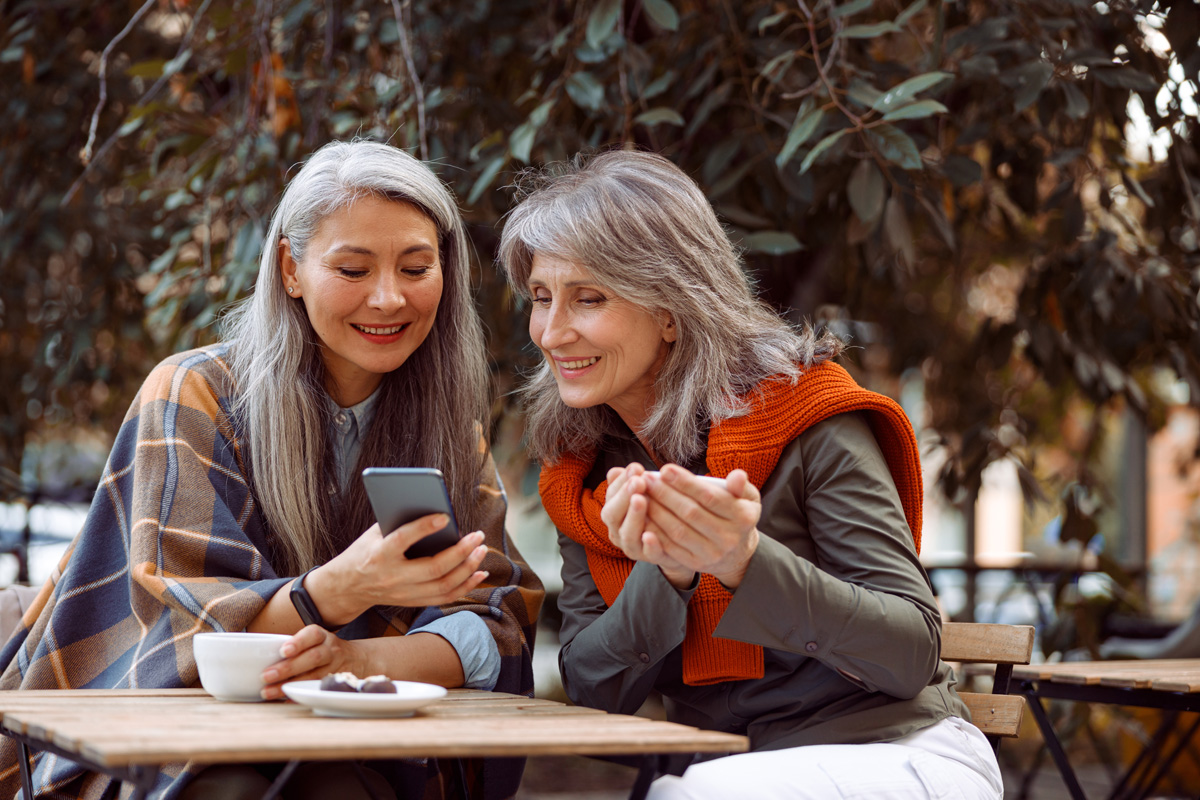 smiling senior Asian lady shows senioridy on phone